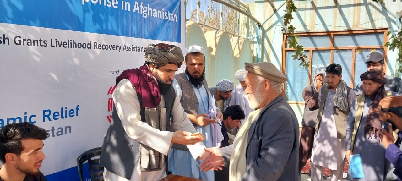 طالبان در حال پخش پول و غذا بین مهاجران افغان +عکس